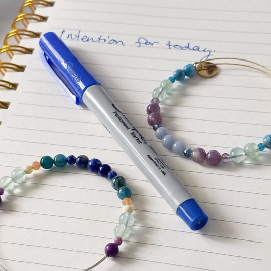 Tranquility and Joy crystal bracelets next to journal and pen – a peaceful ritual for resetting your intention