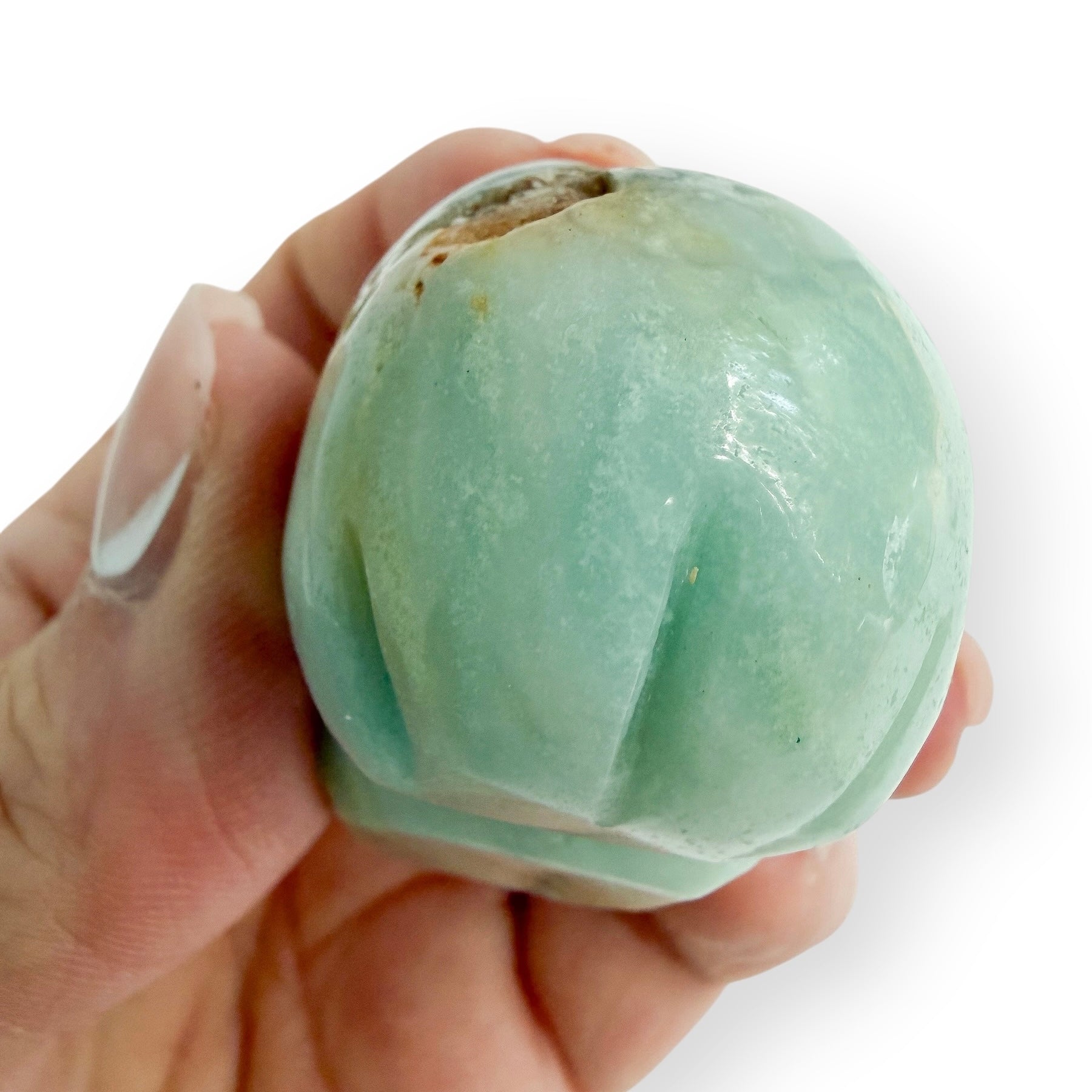 Hand holding a Caribbean calcite skull showing the hand carved detailing of the back of the skull.