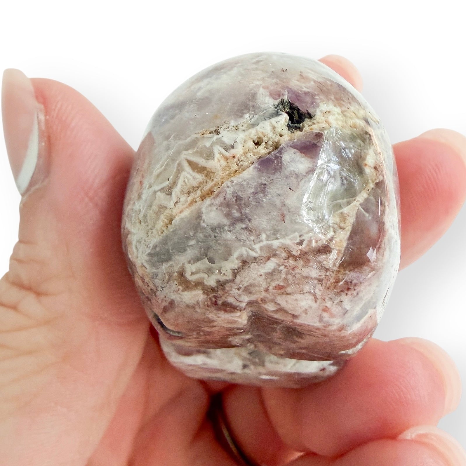 Handholding a light Lepidolite skull in hand to show the back detail of the hand carving.