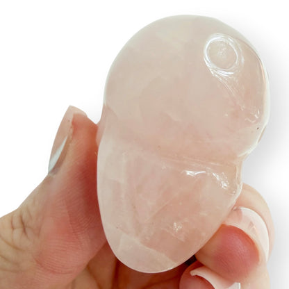 Hand holding A small rose quartz skull to show the base.