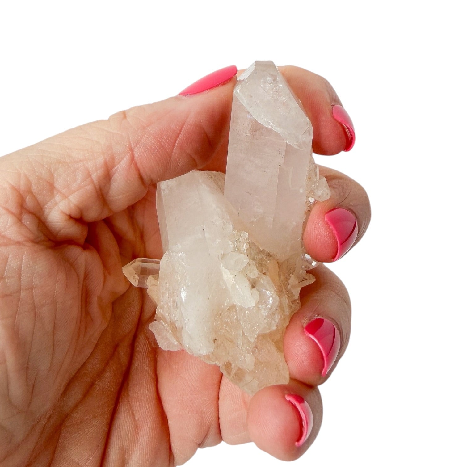 Hand holding a crystal with pink nail polish on a white background