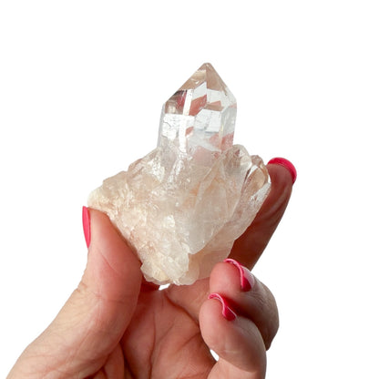 Hand holding a clear crystal with a white background