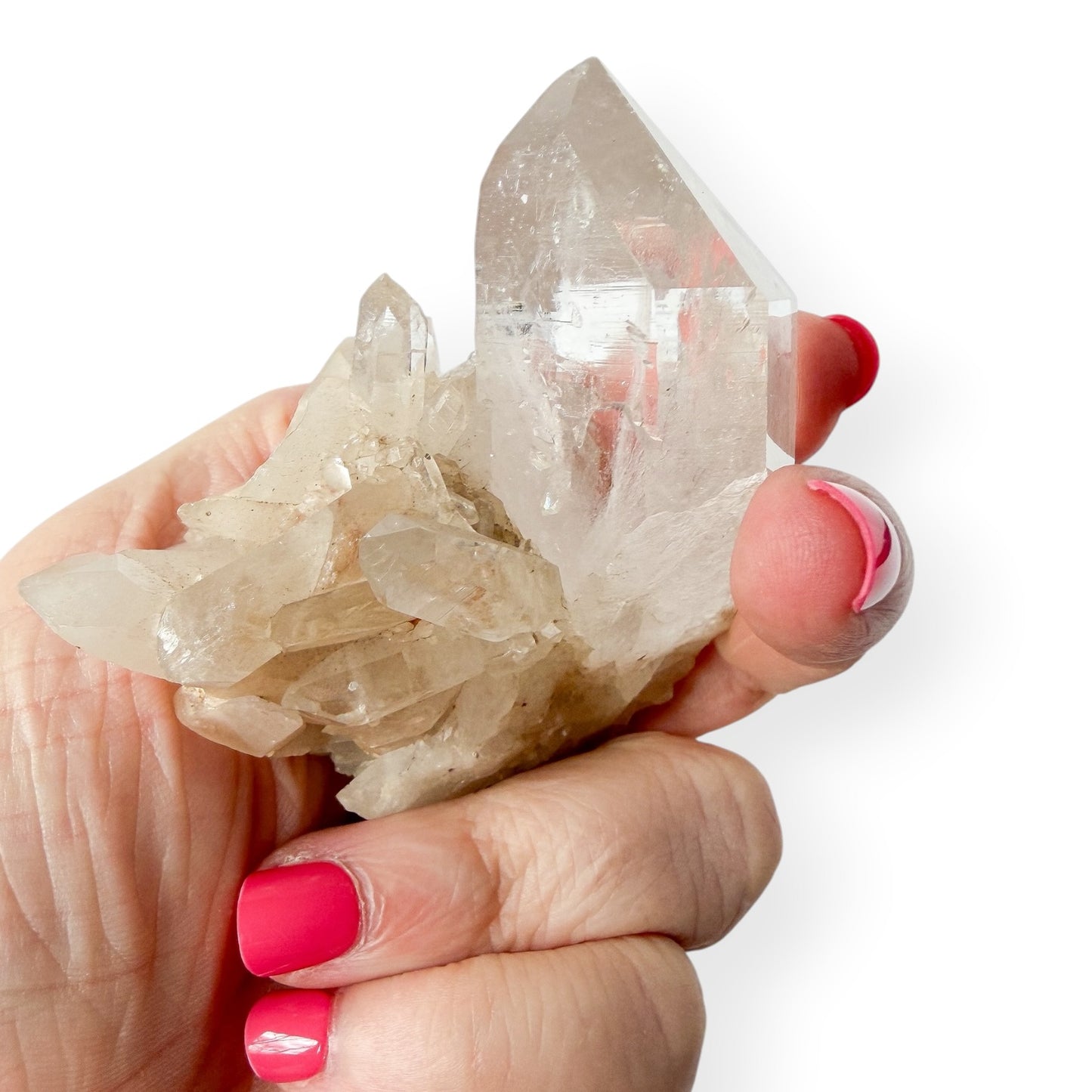 Hand holding a clear crystal with pink nail polish on a white background