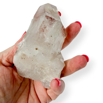 Hand holding a clear crystal quartz rock against a white background