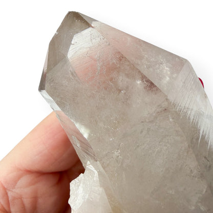 Clear crystal held by a hand against a white background to show details