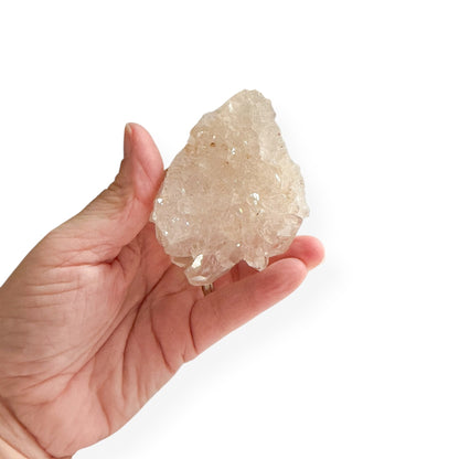 Hand holding a clear quartz crystal rock against a white background