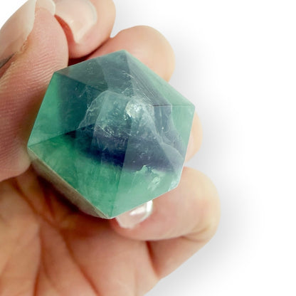 Hand holding a green and purple fluorite obelisk to show the point.