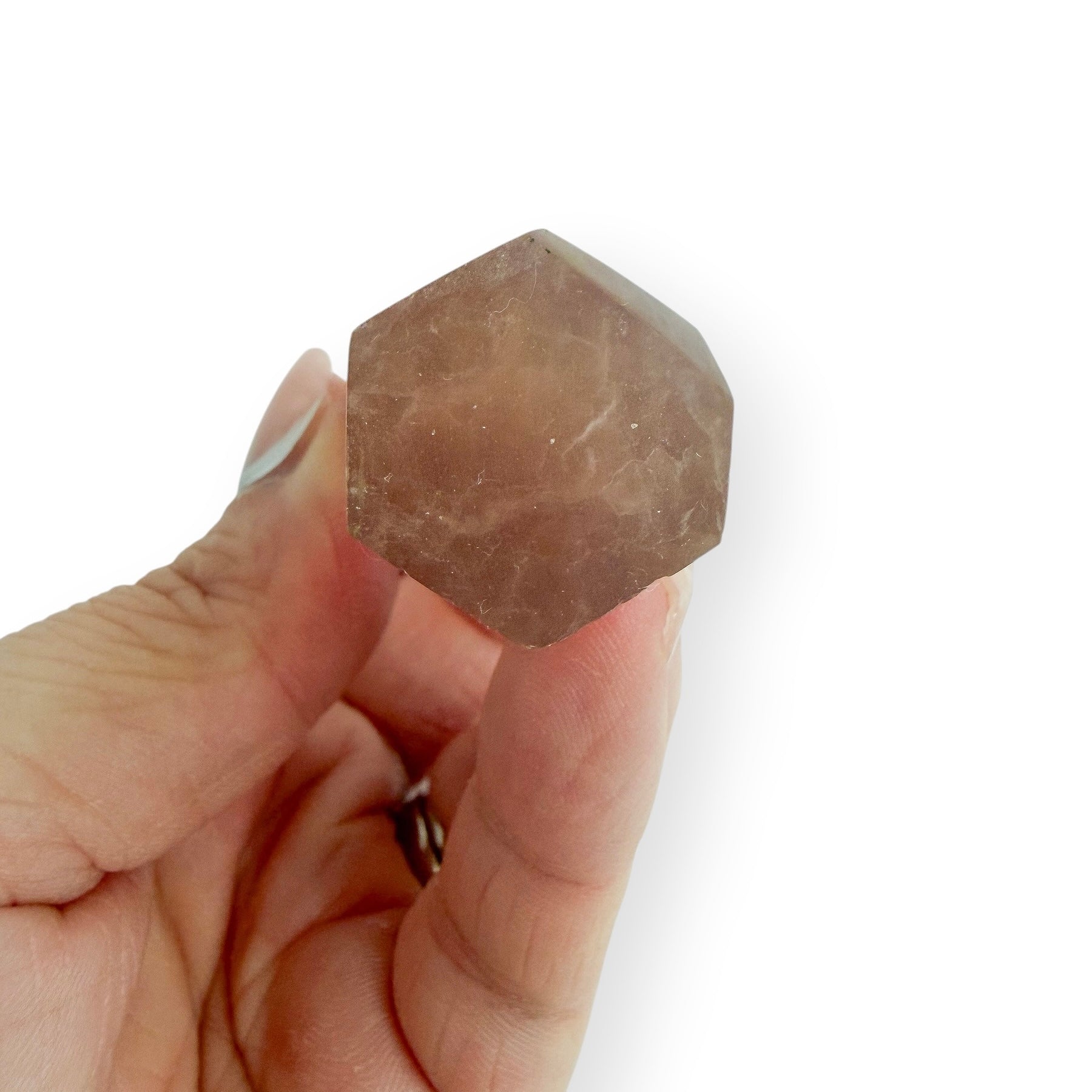Hexagonal base of yellow and purple fluorite crystal held between fingers on a white background