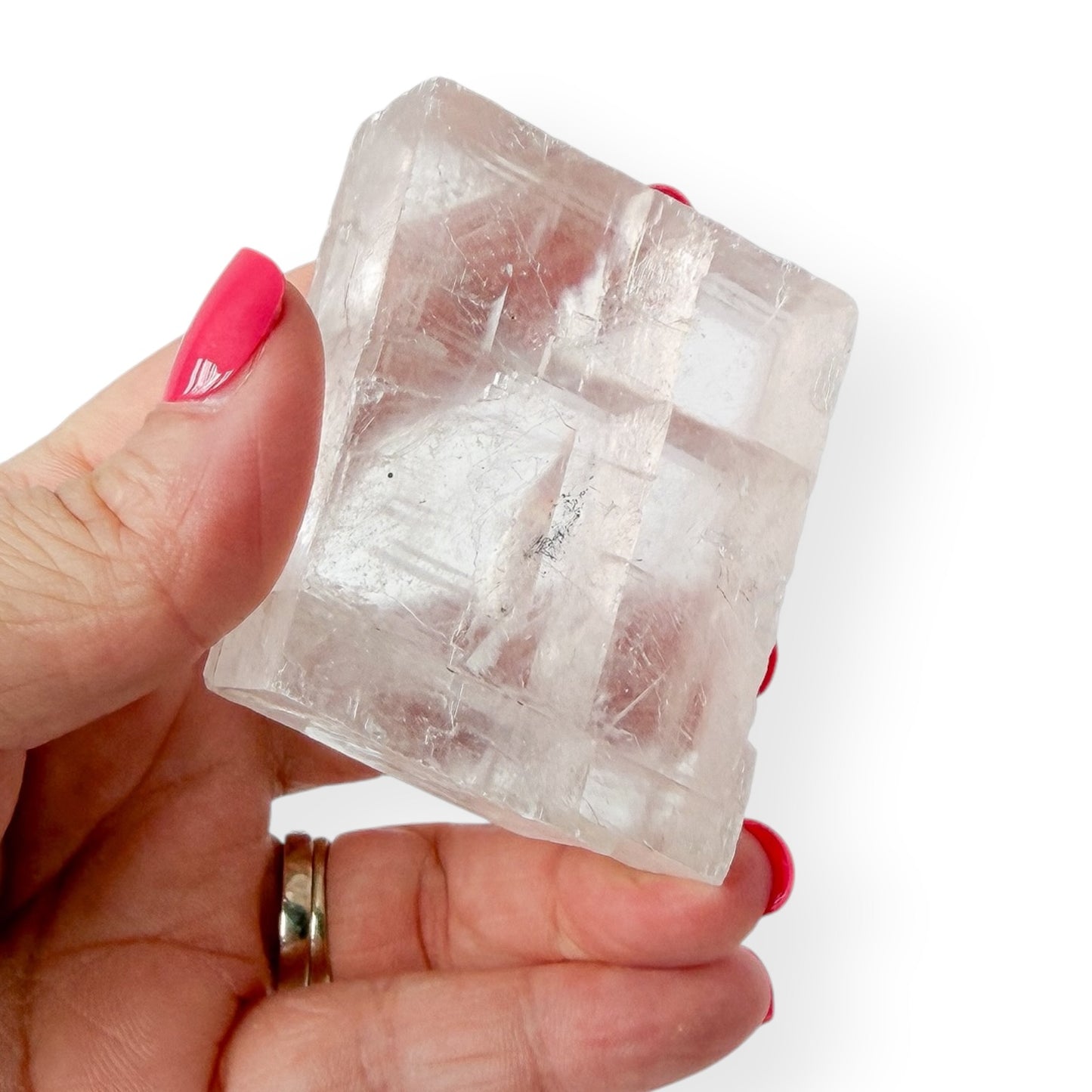 Hand holding a clear optical calcite icelandic spar crystal against a white background in hand for detail