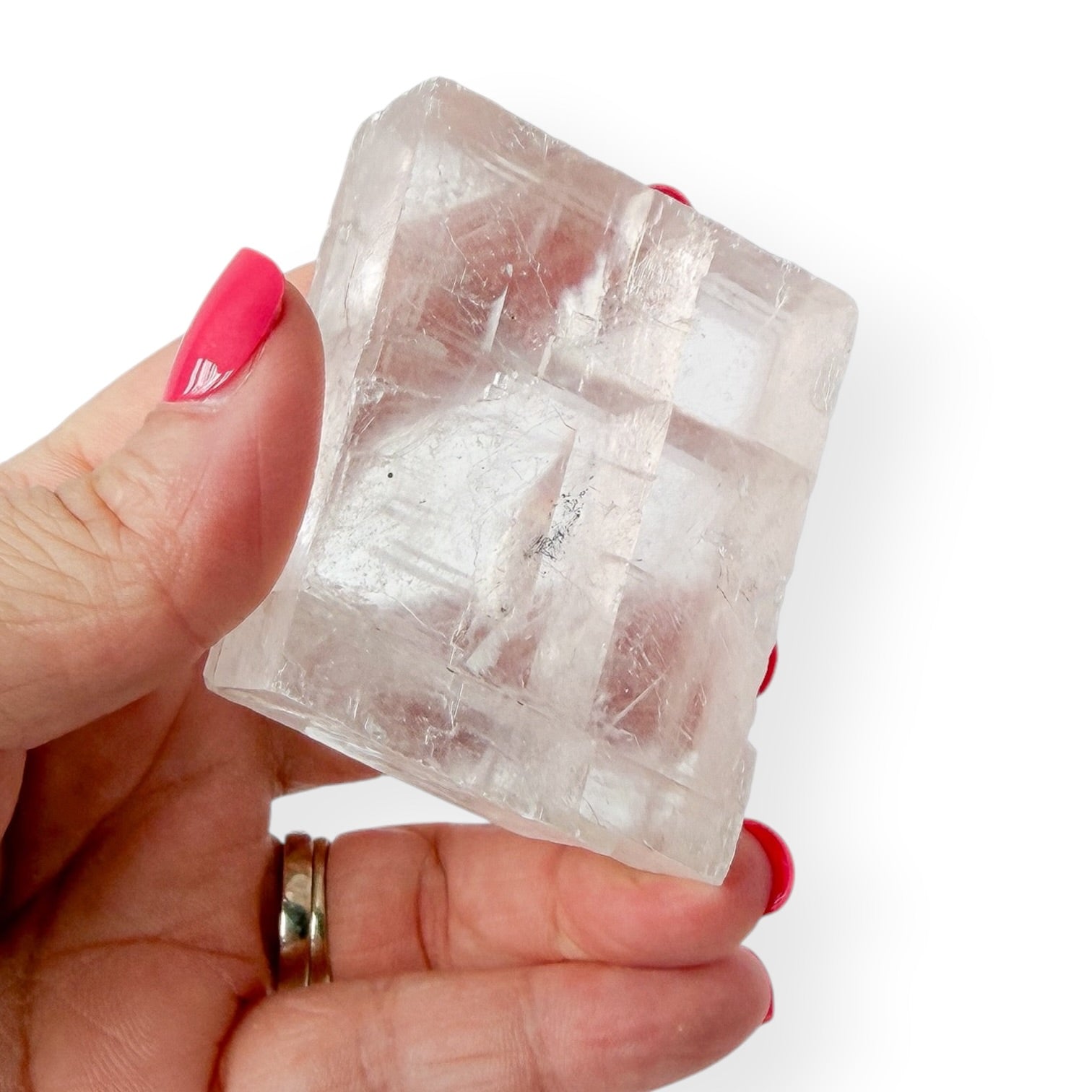 Hand holding a clear optical calcite icelandic spar crystal against a white background in hand for detail
