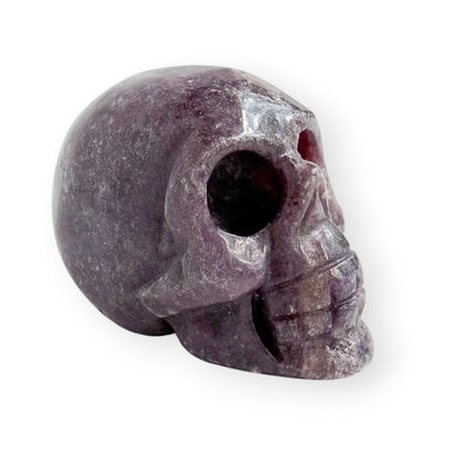 Hand carved lepidolite skull with a white background.