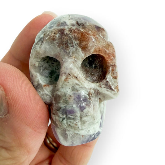 Hand carved light lepidolite skull in hand to show size and detail.