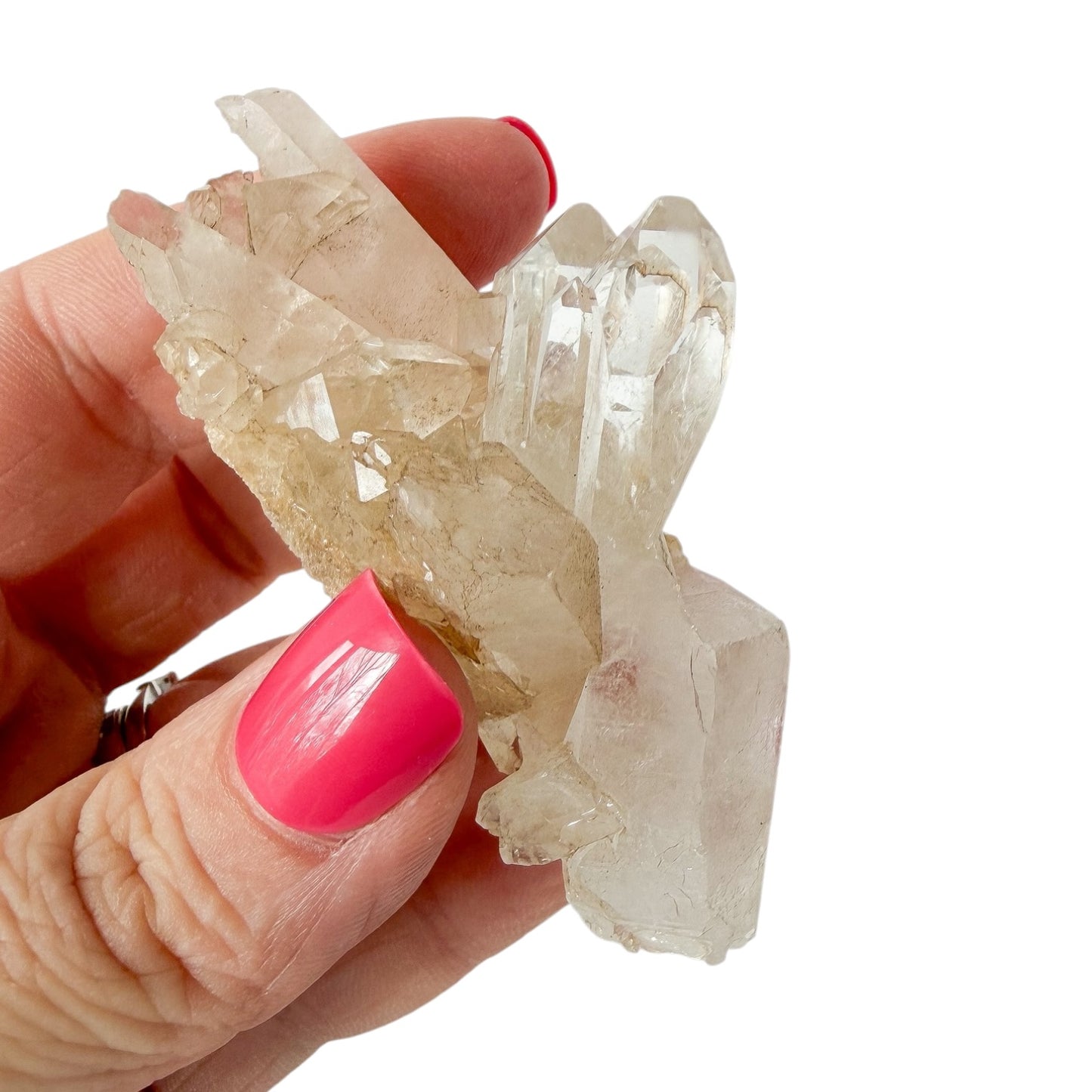 Hand holding a crystal cluster with pink nail polish on a white background