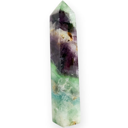 A purple and green fluorite obelisk on a white background with a drusy accent.