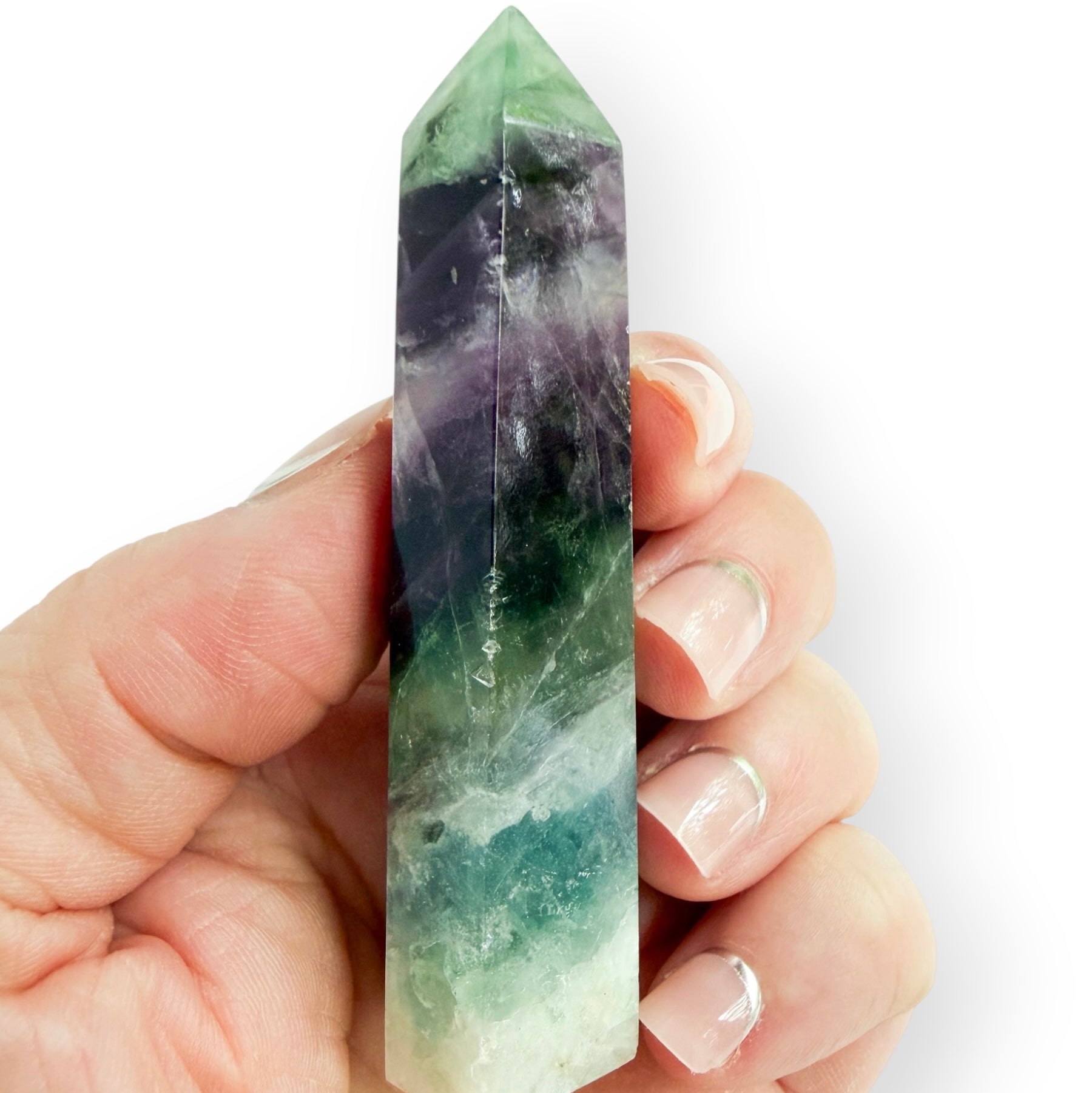 Purple and green fluorite obelisk shown in the hand to show size and detail.