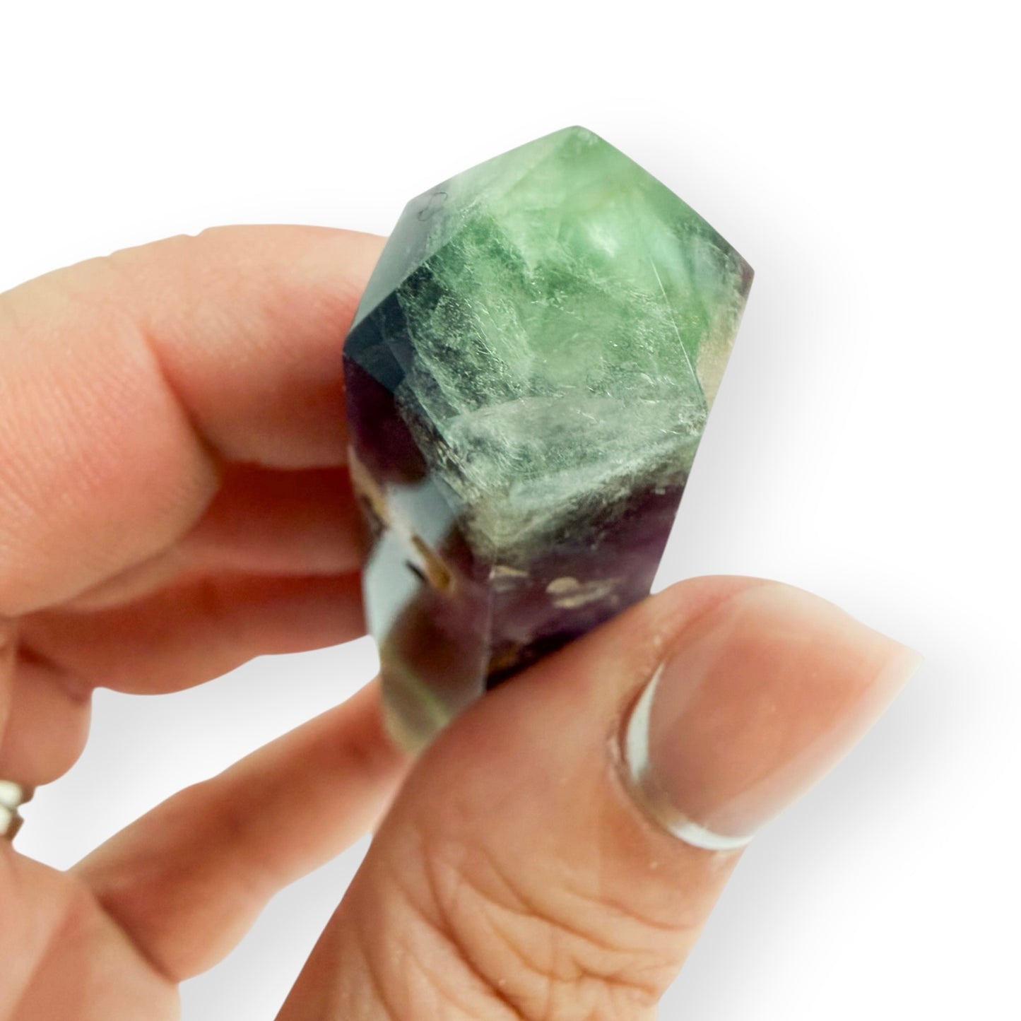 Hand holding a purple and green fluorite oblique to show the point.
