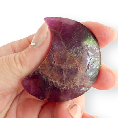 Handheld rainbow fluorite crescent moon carving showing natural purple fluorite patterns and inclusions.