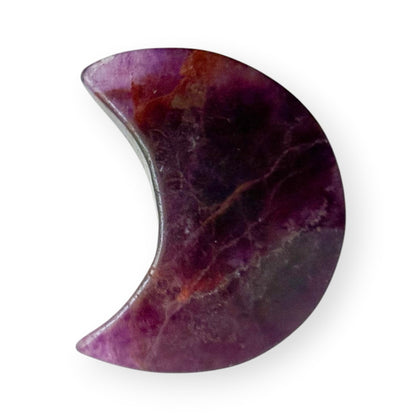 Side profile of a polished rainbow fluorite crescent moon crystal carving with rich purple coloration.