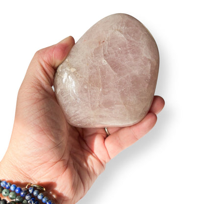 Hand holding a large pink stone against a white background