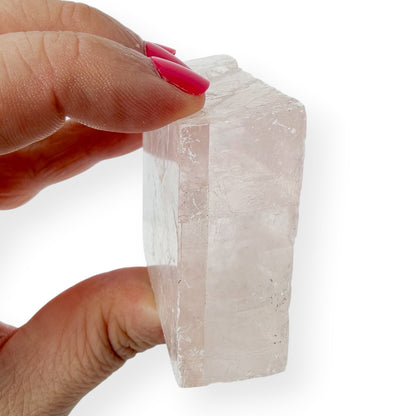 Hand holding a clear optical calcite side view against a white background to show detail
