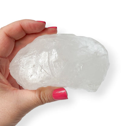 Hand holding a large white calcite crystal rock against a white background