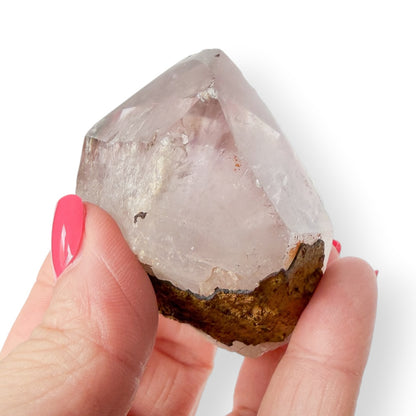 Hand holding an Amethyst crystal with a white background