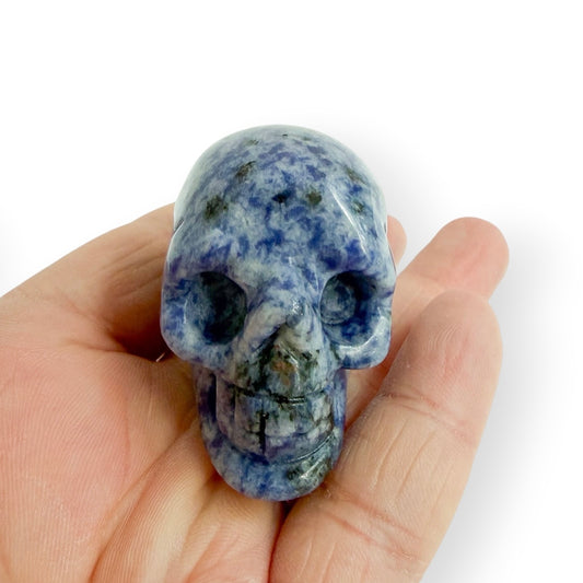 Hand holding sodalite skull to show size and detail.