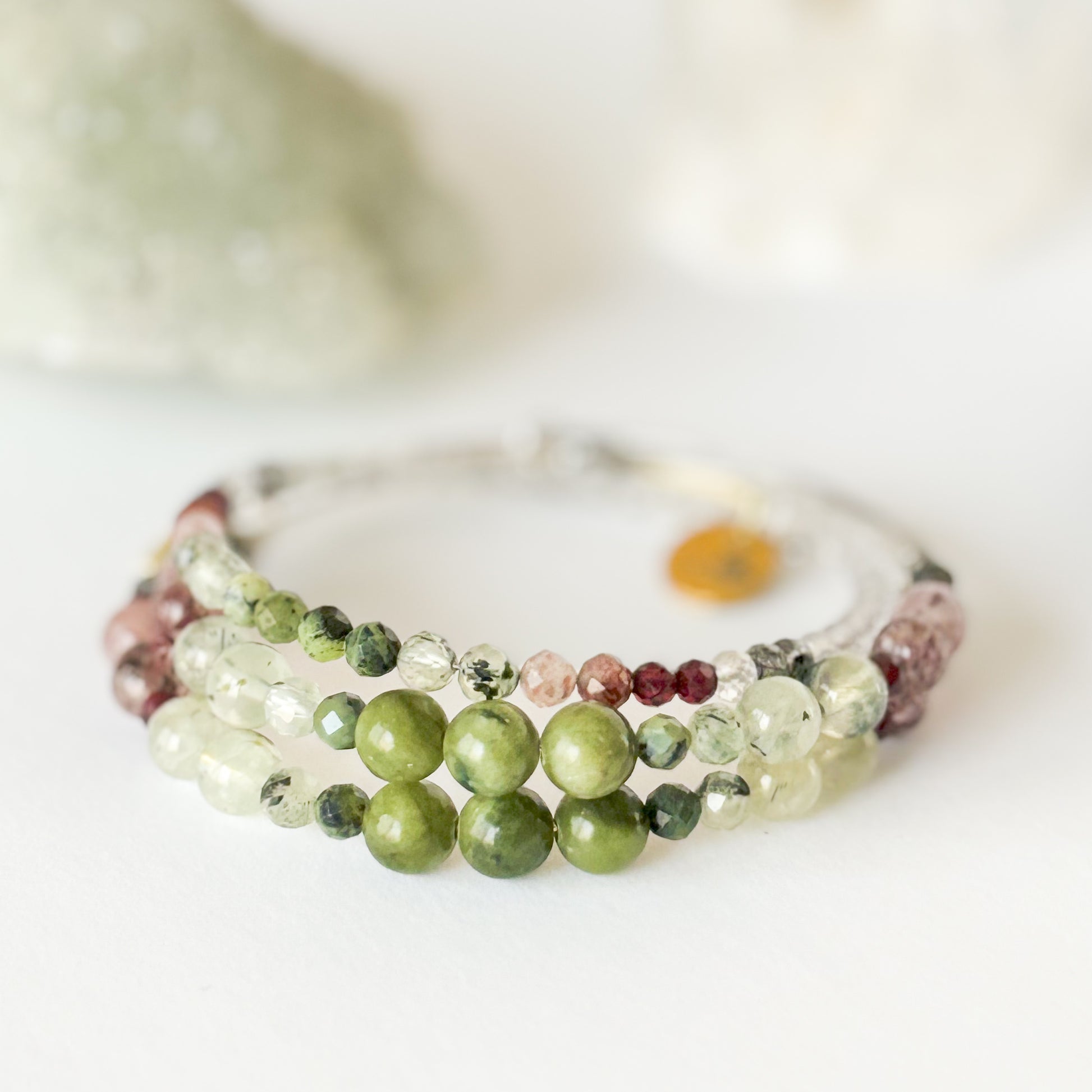 Flatlay of Tenacious Wrap Bracelet showing blend of green, pink, and deep red crystal beads.