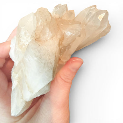 Hand holding a large crystal cluster against a white background