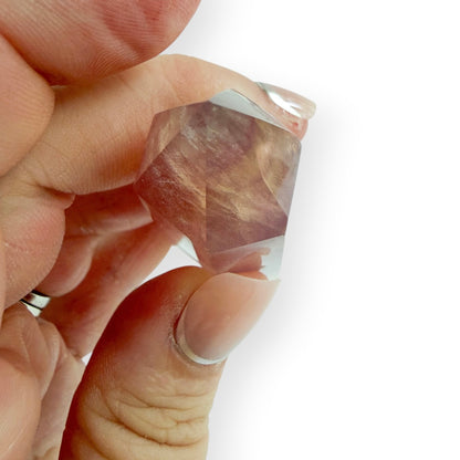 Hand holding a yellow and purple striped fluorite obelisk showing the point.