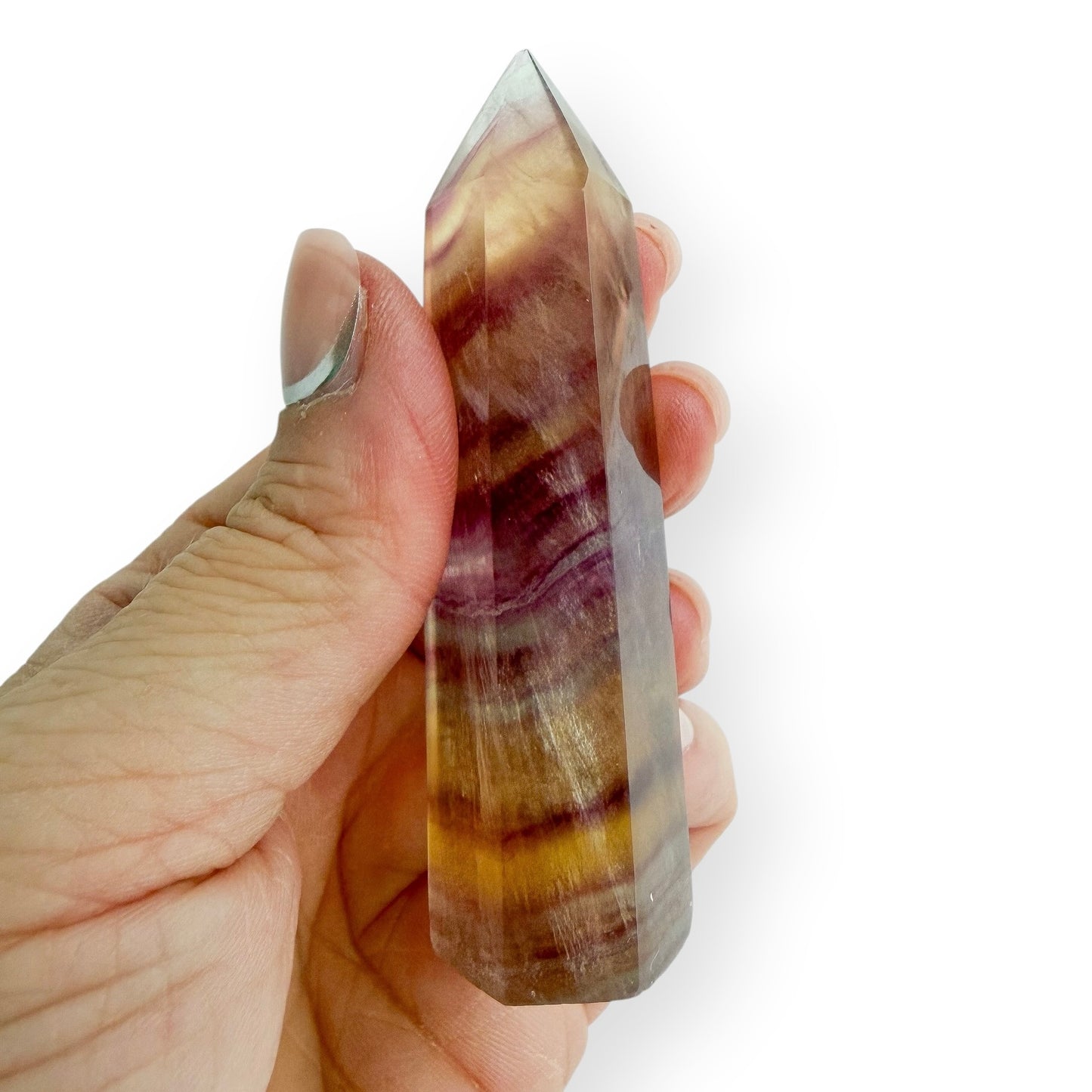 Yellow and purple striped fluorite in hand to show details in size.