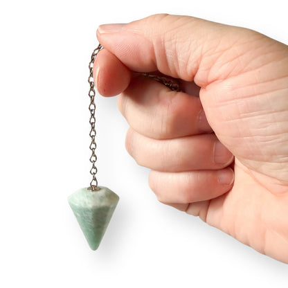 Hand holding amazonite pendulum dowsing tool showing natural blue green crystal detail