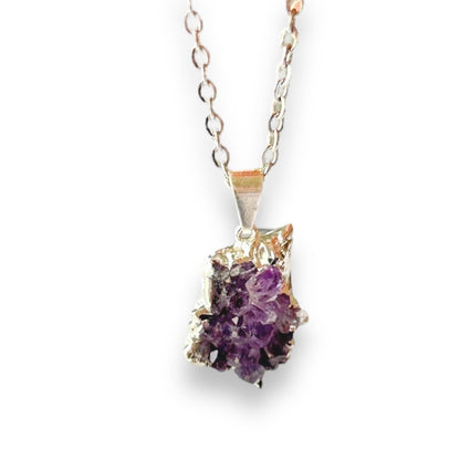 Amethyst drusy necklace with raw purple crystal and silver-toned edge on white background