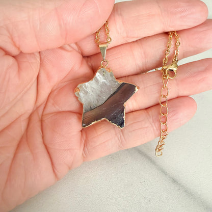 Close up of gold plated amethyst star pendant highlighting natural crystal texture and subtle purple coloring.