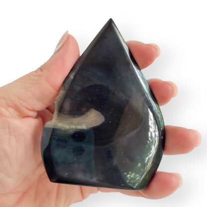 Hand holding black agate teardrop freestanding Freeform in hand to show the back details of crystal.