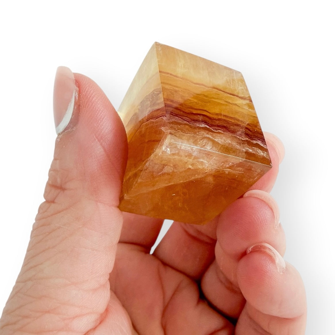 Honey and Amber Fluorite freeform held in hand, displaying striking layered banding and translucent golden tones.