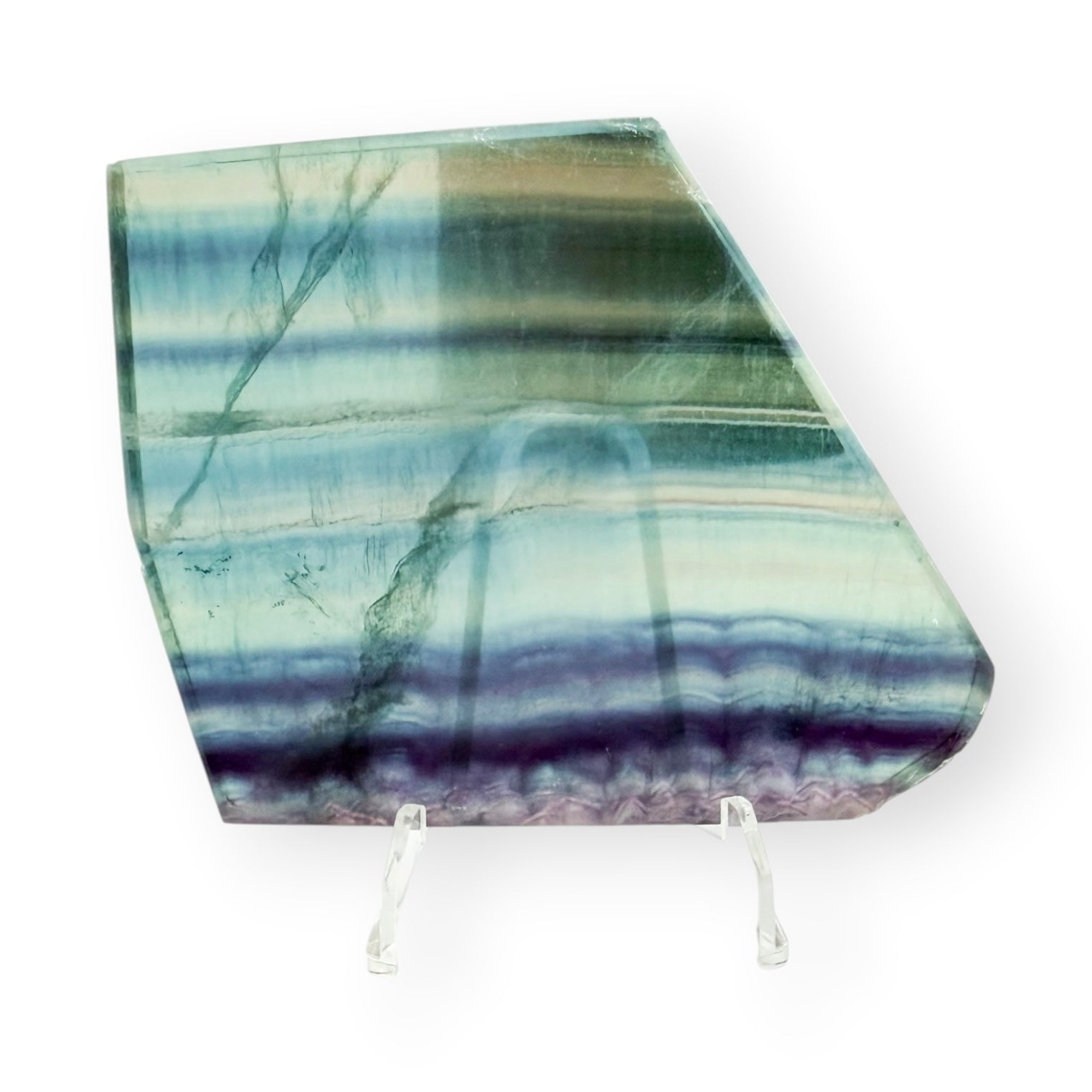 Rainbow Fluorite slab with blue, green, and purple bands displayed on a clear stand.