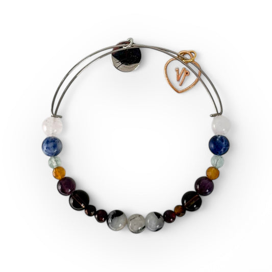 Capricorn Crystal Charm Bracelet with a white charm, handcrafted with Garnet, Tiger’s Eye, Smoky Quartz, Amethyst, Citrine, and Fluorite for success and resilience.