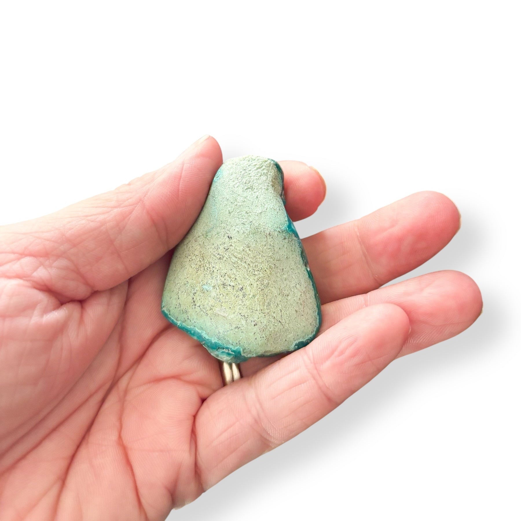 Back of Chrysocolla pocket stone with raw green matrix held in hand