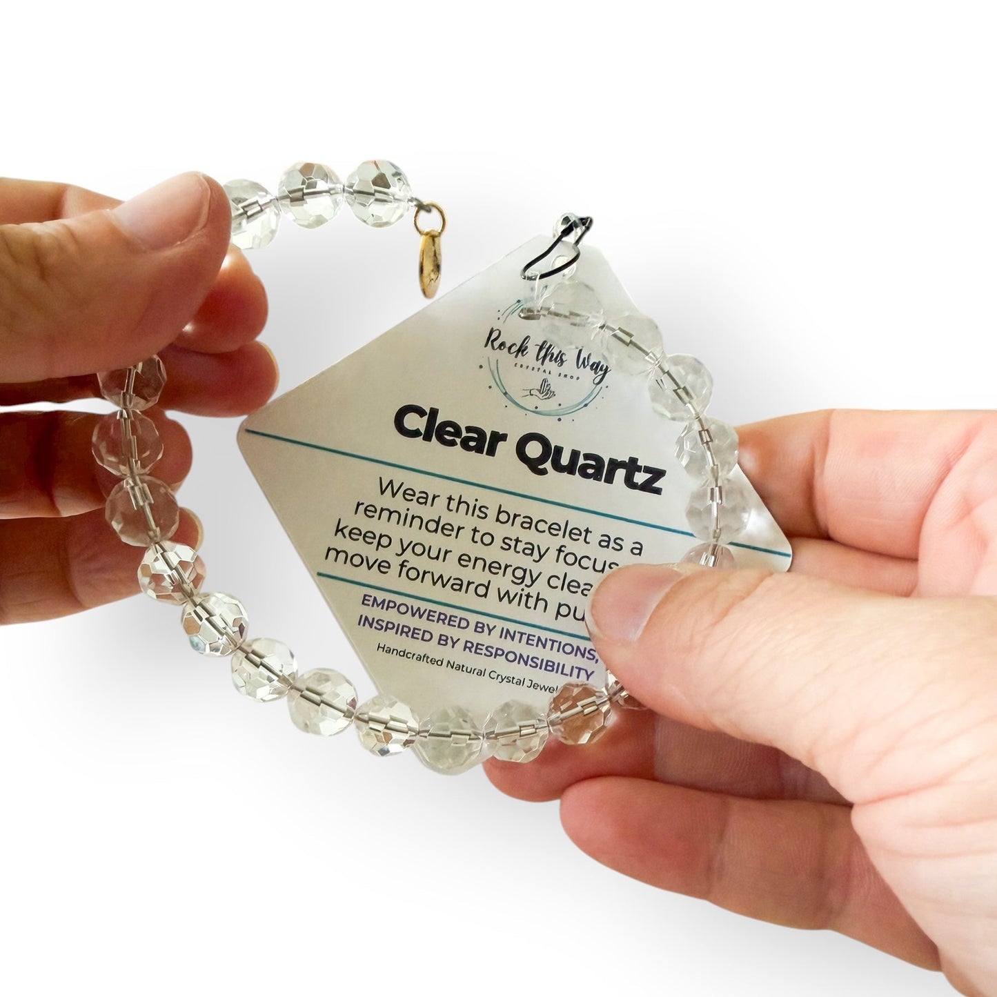 Clear Quartz 10mm micro-faceted bracelet held in hands with the Rock This Way meaning card.