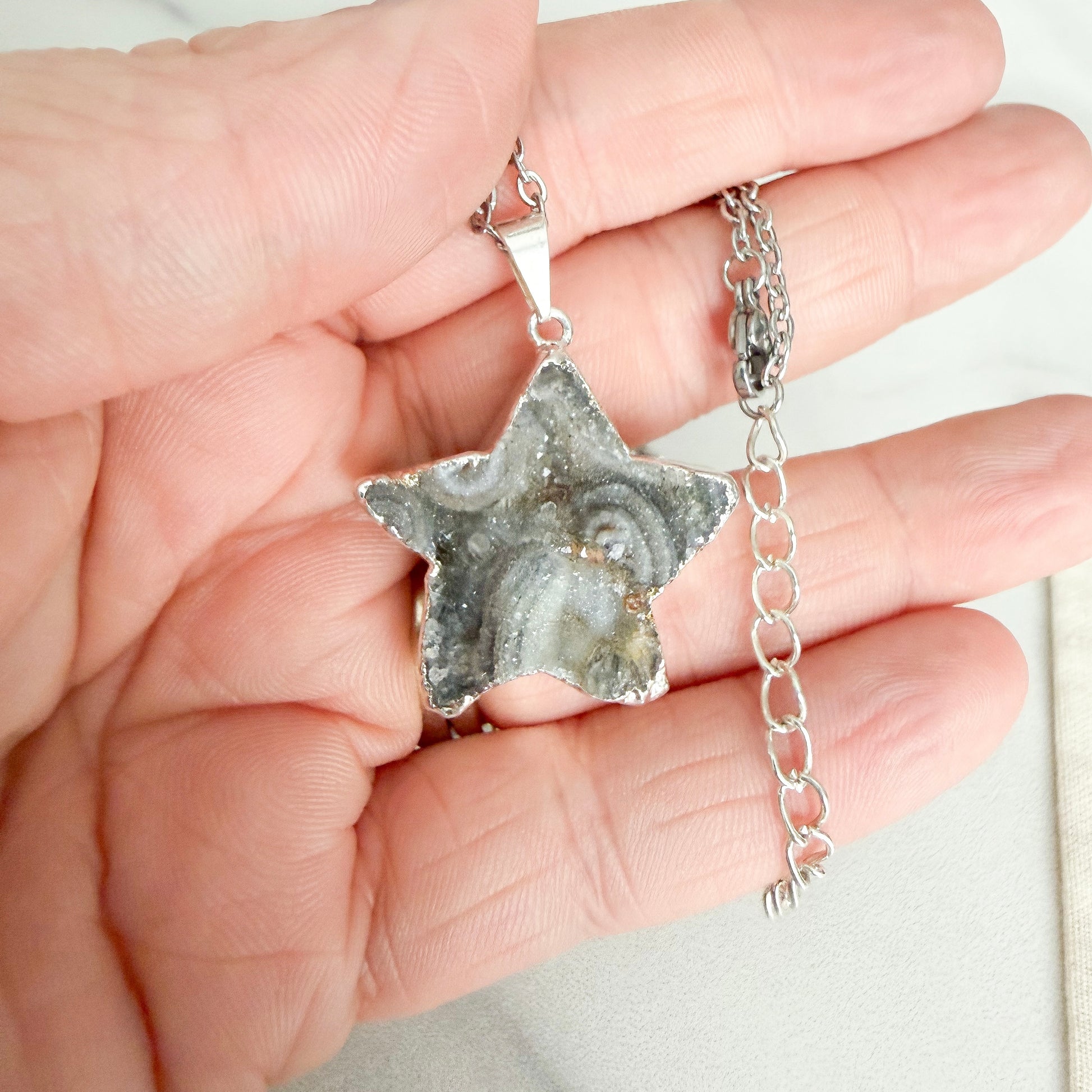 Close up detail ofsStar shaped drusy crystal silver plated pendant necklace on stainless steel chain