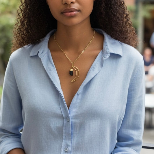 Modeled view of a gold plated crescent moon necklace with black tourmaline crystal on a PVD gold plated stainless steel chain, shown in an AI generated lifestyle image.