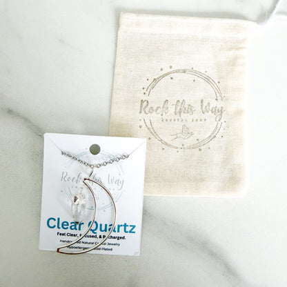 Silver plated crescent moon with clear quartz pendant necklace displayed on Rock This Way Crystal Shop packaging with included polishing cloth.