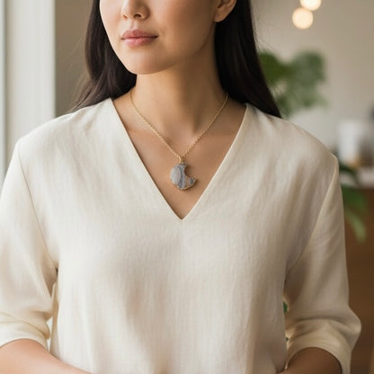 Modeled view of a gold plated crescent moon drusy pendant necklace on a PVD gold plated stainless steel chain, shown in an AI generated lifestyle image.