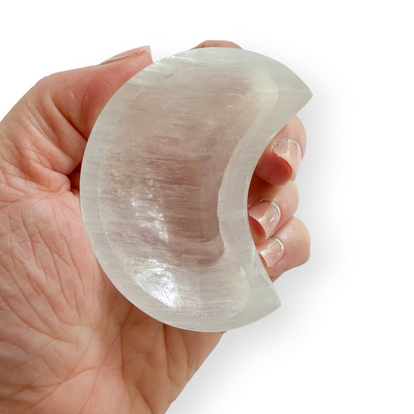 Hand holding Carved Satin Spar crescent moon dish featuring translucent white coloring and a natural pearly glow.