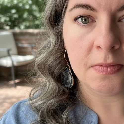 Model wearing dark agate slice geode earrings with gold filled ear wires and long drop design