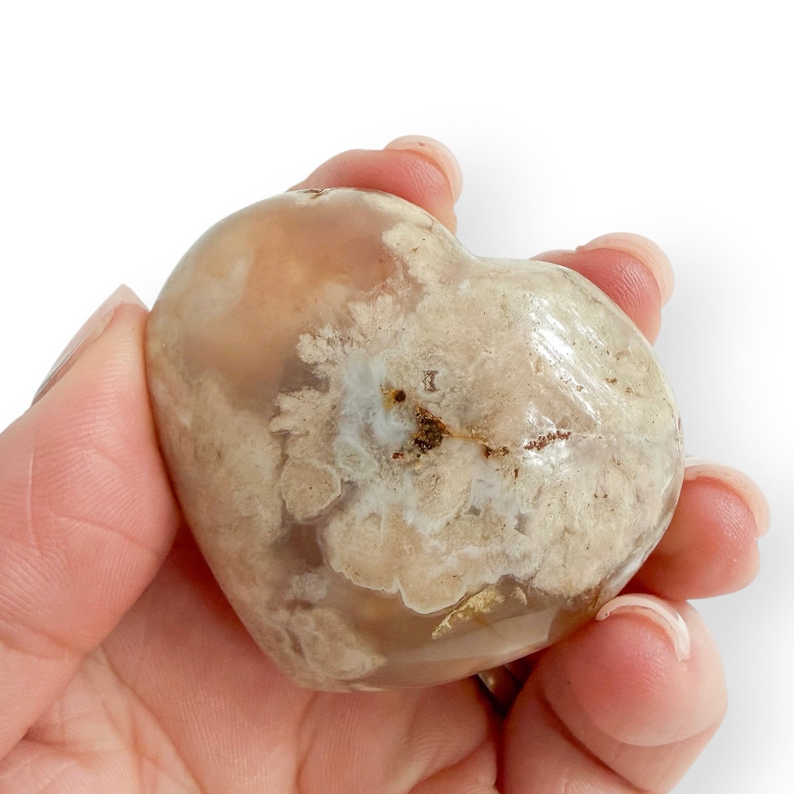 Hand holding a Madagascar Flower Agate heart displaying natural flower-like inclusions and soft neutral tones.