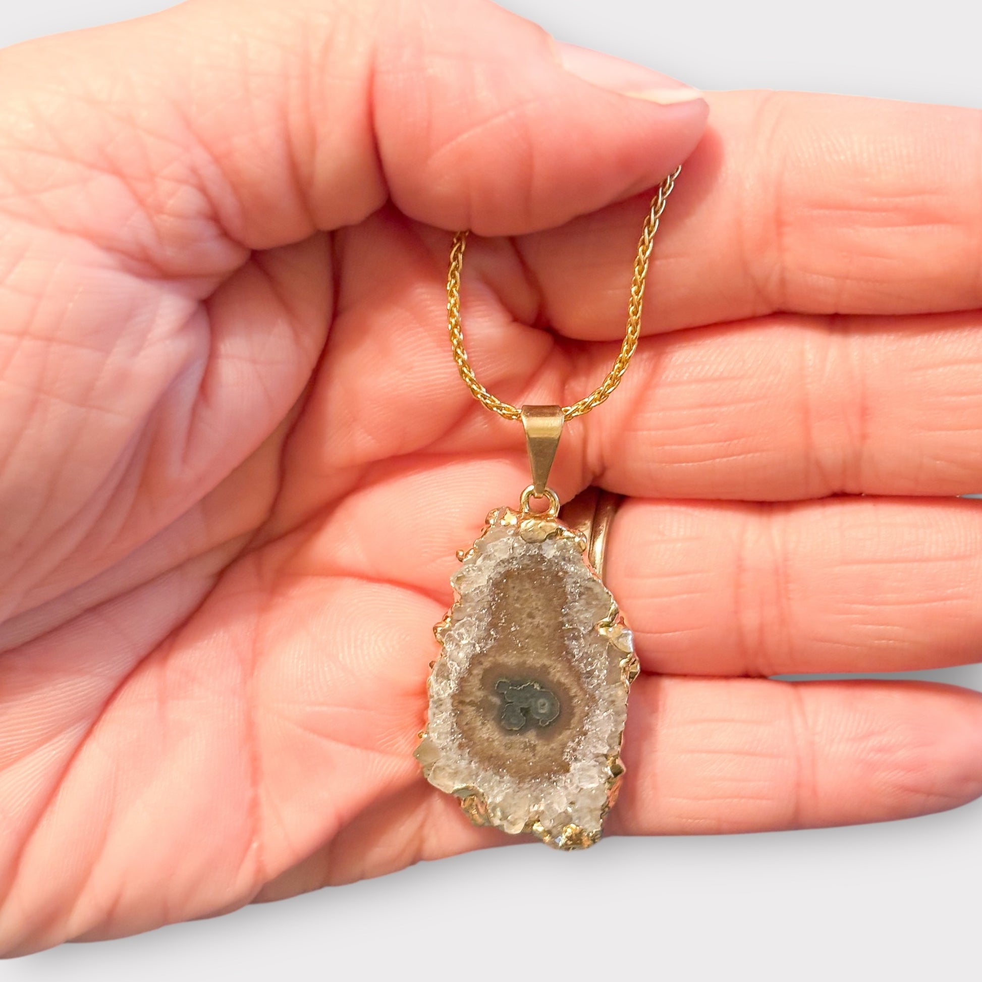 Close-up of amethyst stalactite pendant showing lilac, taupe, and green crystal center