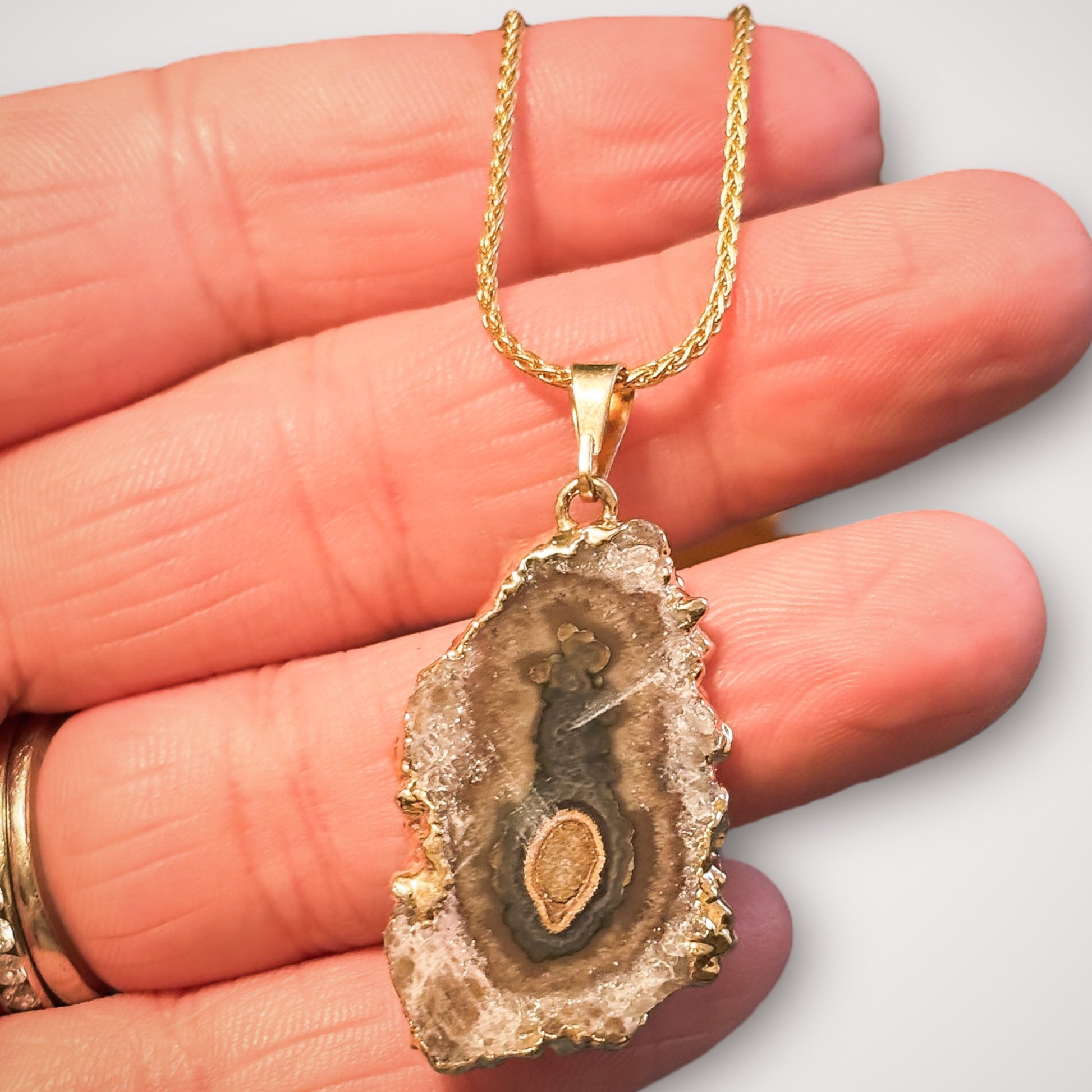 Gold amethyst stalactite necklace resting in palm of hand to show scale