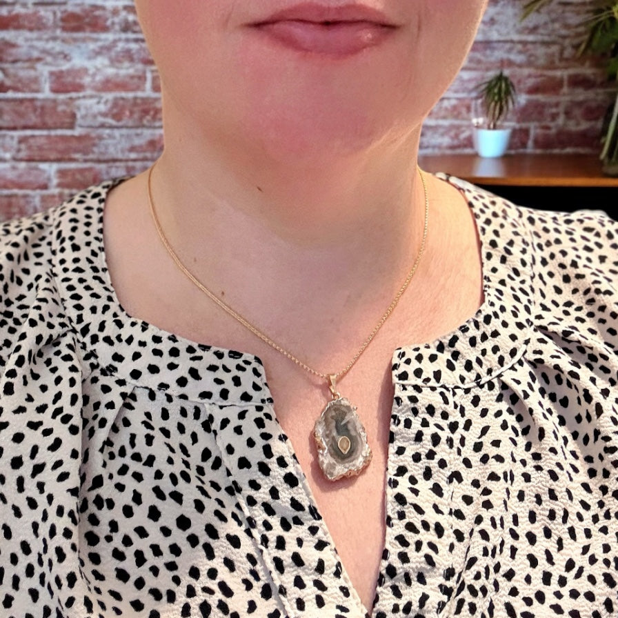 Woman wearing gold amethyst stalactite necklace with soft purple and green tones